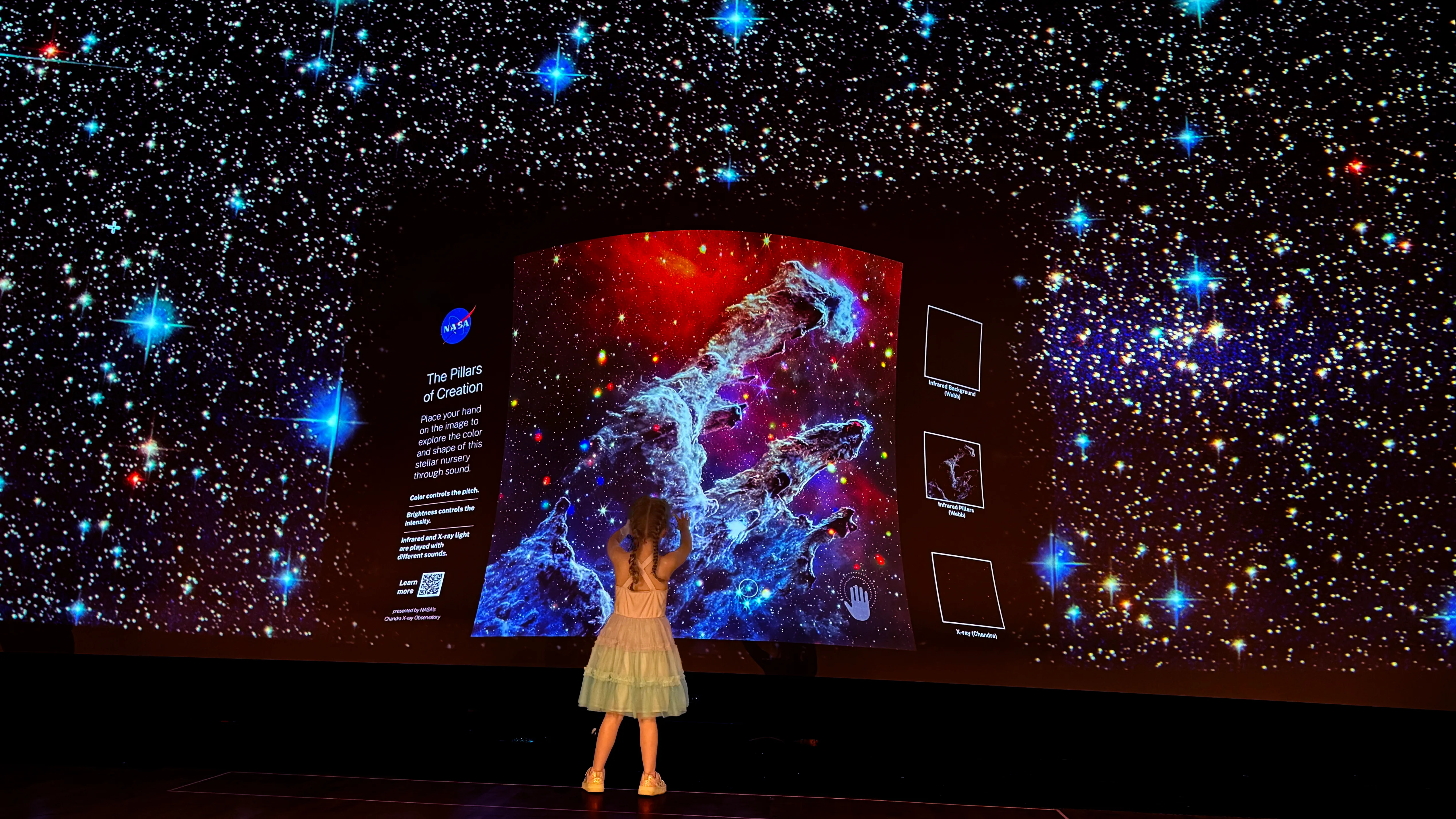 A young girl raising her hand up to the Pillars of Creation.